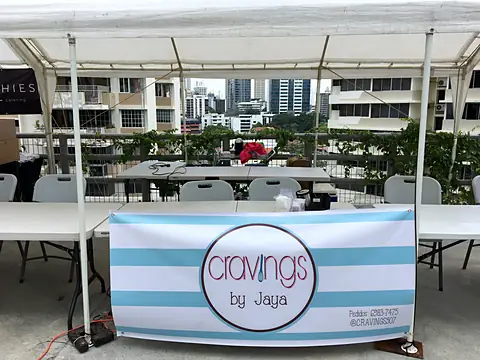 Puesto de Cravings by Jaya con su letrero de rayas, 2018